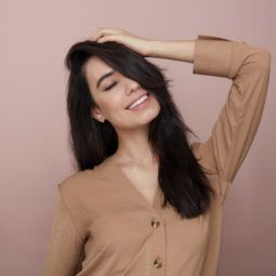 What is a hair mask: Woman touching her long dark brown hair, wearing brown nude jumper in the All Things Hair UK Studio