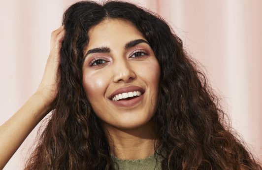 Woman with thick long curly hair touching her head