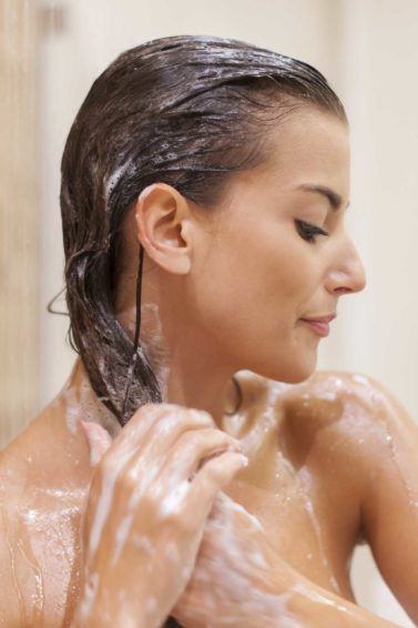 brunette woman in the shower washing her hair