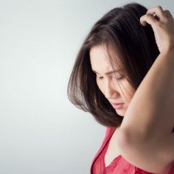 itchy scalp dry scalp woman in red top touching and inspecting her scalp