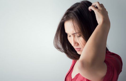 itchy scalp dry scalp woman in red top touching and inspecting her scalp