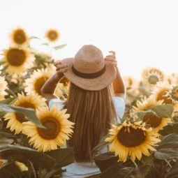 World Earth Day: Woman in a sunflower field with long hair with sunhat on