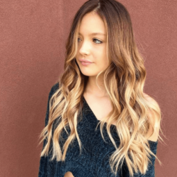 front facing image of a woman with long wavy hair - blonde brown hair