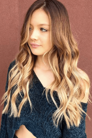 front facing image of a woman with long wavy hair - blonde brown hair